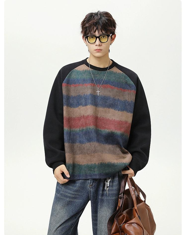 A young man wearing a striped sweater, sunglasses, and holding a brown bag stands against a white background.