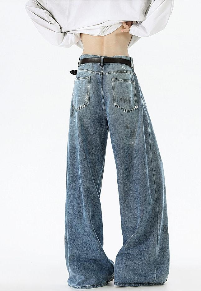 A person wearing wide-leg jeans and a white shirt stands with their back to the camera.