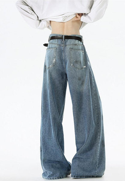 A person wearing wide-leg jeans and a white shirt stands with their back to the camera.