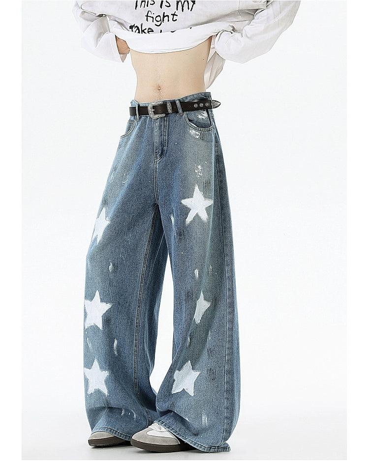 A person wearing a white shirt with black text and blue jeans with white stars printed on them.