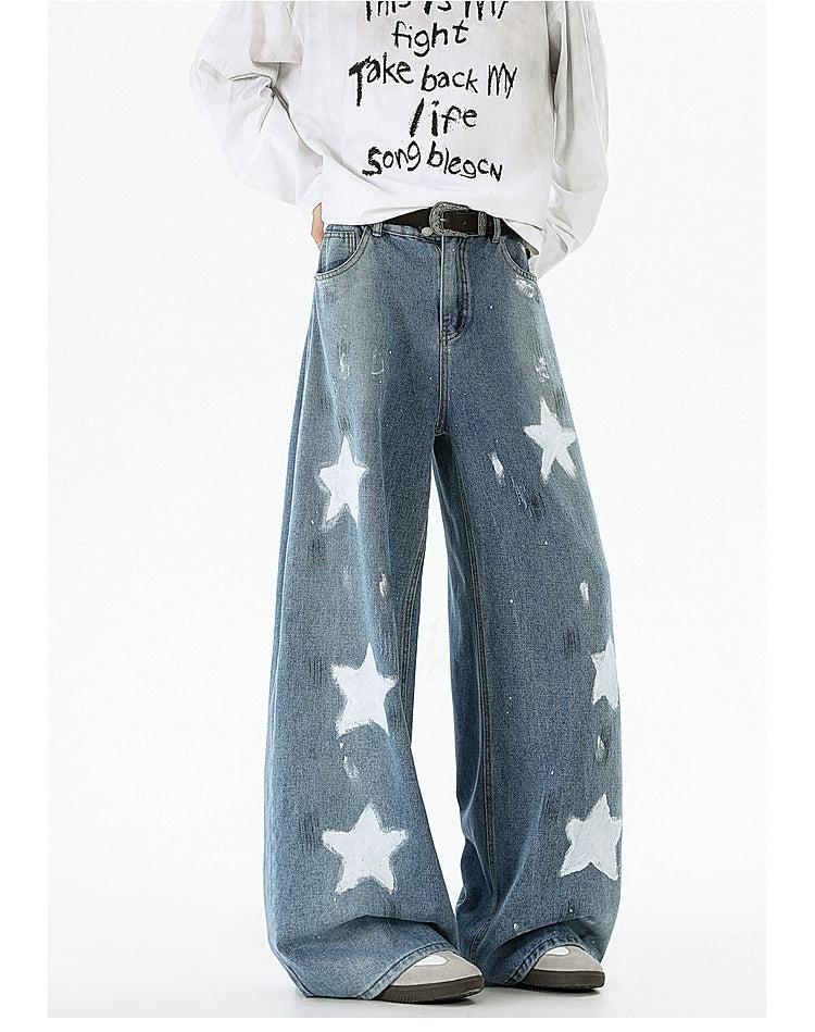 A person wearing a white sweatshirt with black text and blue jeans with white star patterns.